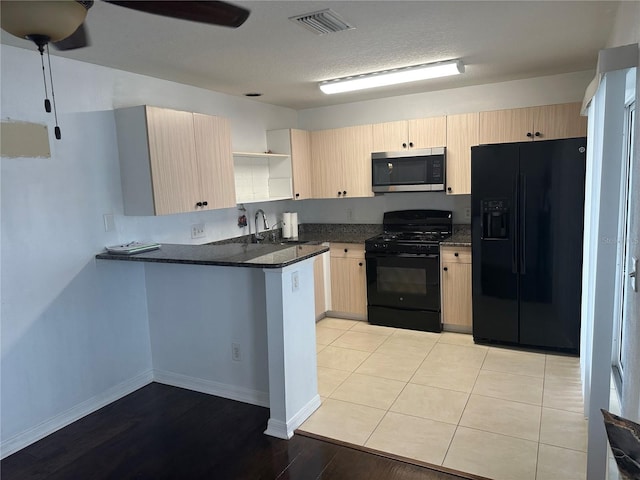 kitchen featuring sink, dark stone countertops, black appliances, kitchen peninsula, and light brown cabinets