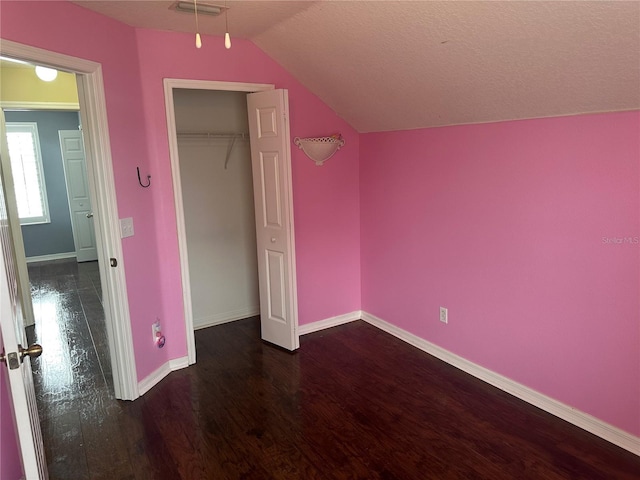 unfurnished bedroom featuring lofted ceiling, dark hardwood / wood-style flooring, and a closet