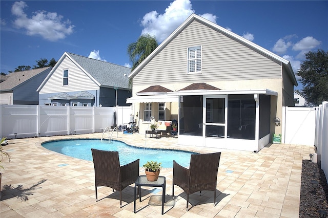 rear view of house with a fenced in pool, a patio area, and a sunroom