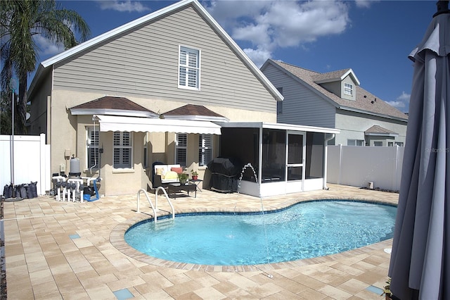 back of property with a fenced in pool, a patio area, and a sunroom