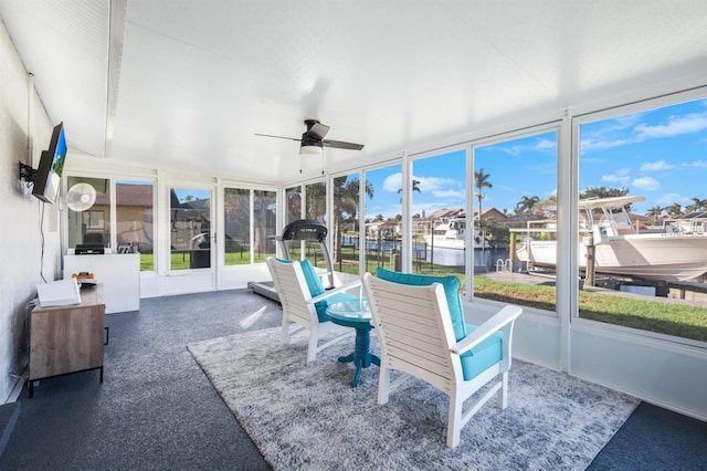 sunroom with a water view and ceiling fan