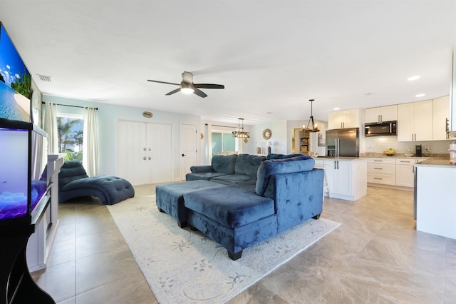 living room featuring ceiling fan with notable chandelier