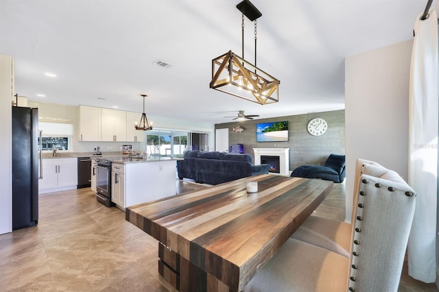 dining area featuring wood walls, sink, and ceiling fan