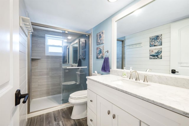 bathroom featuring toilet, hardwood / wood-style floors, vanity, and a shower with door