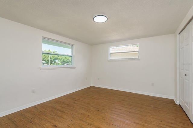 empty room with wood-type flooring and a textured ceiling