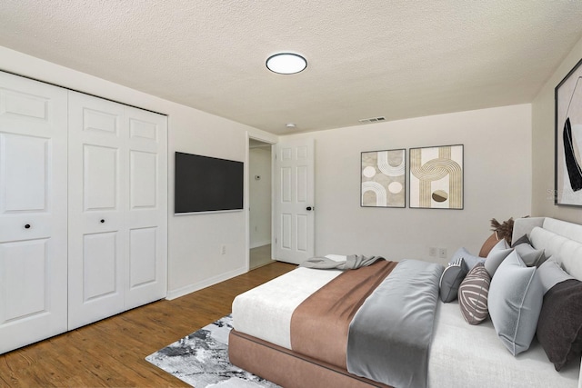 bedroom with a closet, wood-type flooring, and a textured ceiling