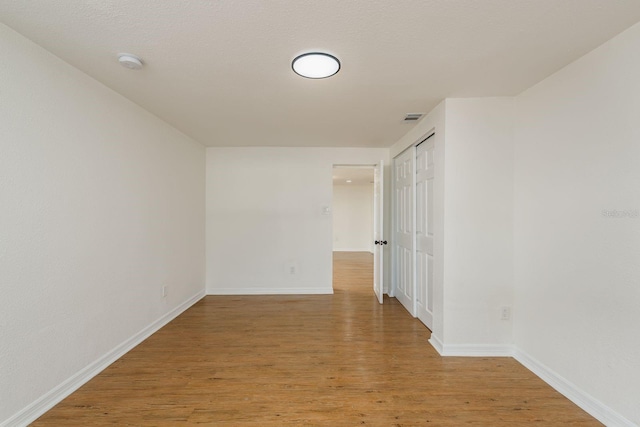 unfurnished room with a textured ceiling and light wood-type flooring