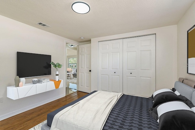 bedroom featuring wood-type flooring, a textured ceiling, and a closet