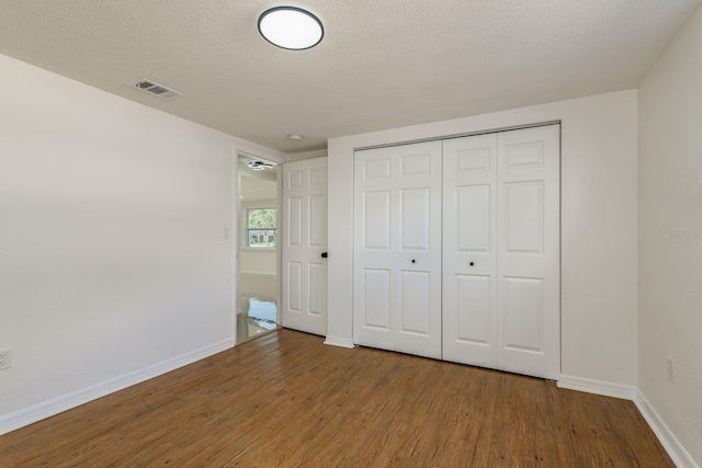 unfurnished bedroom featuring wood-type flooring, a closet, and a textured ceiling