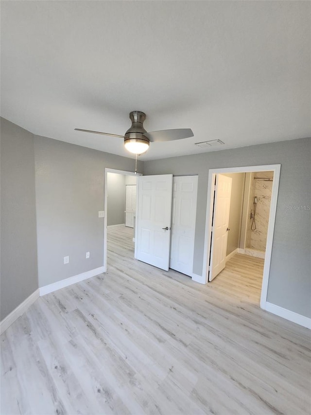 unfurnished bedroom with ensuite bathroom, light wood-type flooring, and ceiling fan