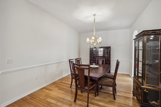 dining space with light hardwood / wood-style floors and a notable chandelier