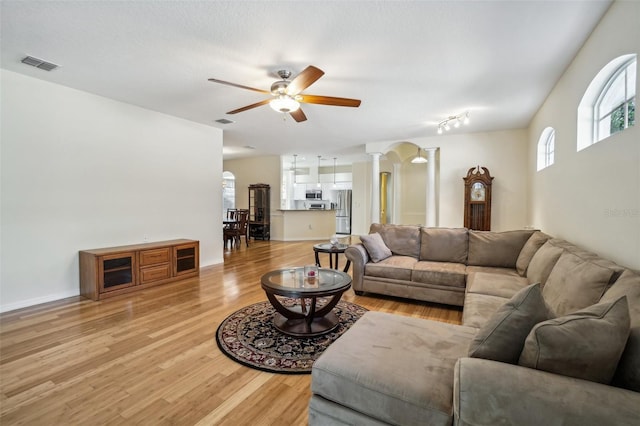 living room with ornate columns, ceiling fan, and light wood-type flooring