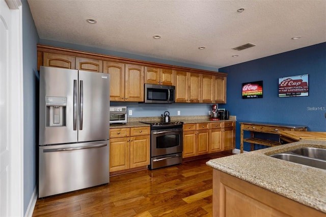 kitchen featuring appliances with stainless steel finishes, a textured ceiling, sink, and dark hardwood / wood-style flooring