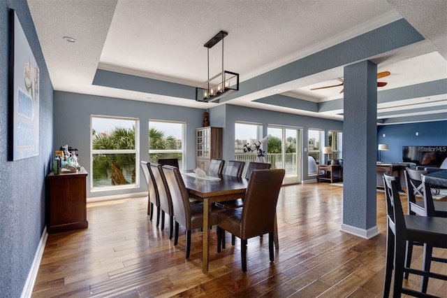 dining space with a textured ceiling, hardwood / wood-style flooring, and a raised ceiling