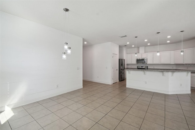 kitchen featuring a kitchen breakfast bar, white cabinetry, stainless steel appliances, and decorative light fixtures