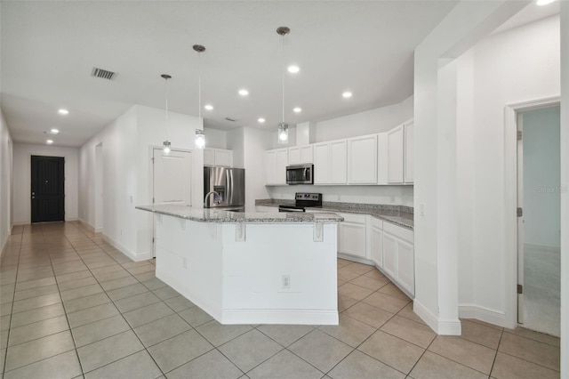 kitchen featuring light stone countertops, white cabinetry, an island with sink, and stainless steel appliances