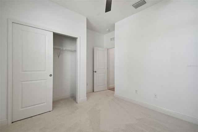 unfurnished bedroom featuring light carpet, a closet, and ceiling fan