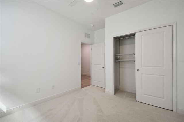 unfurnished bedroom featuring light carpet, a closet, and ceiling fan