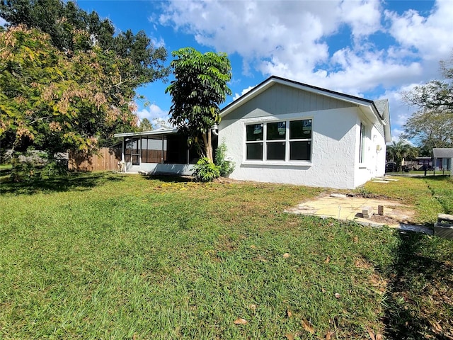 back of property with a lawn and a sunroom