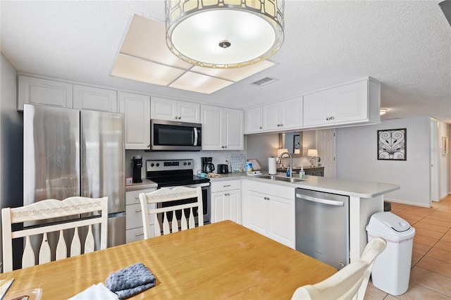 kitchen with kitchen peninsula, white cabinets, sink, and appliances with stainless steel finishes