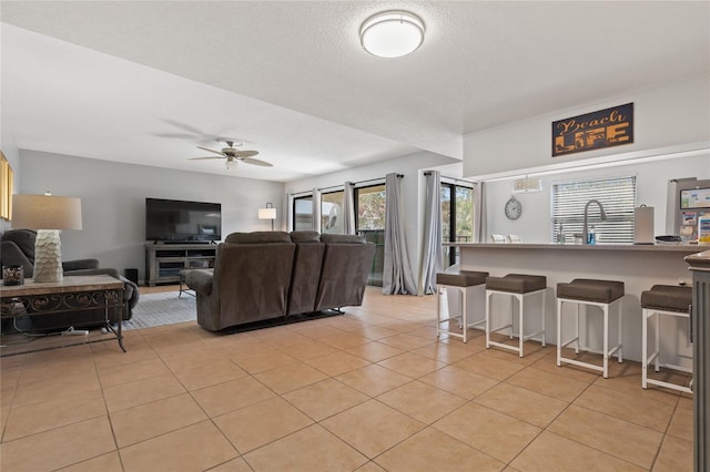 living room featuring sink, a textured ceiling, light tile patterned floors, and ceiling fan