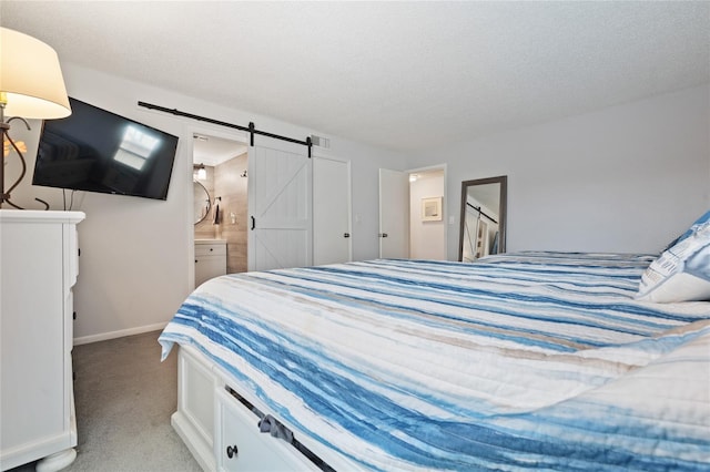 carpeted bedroom featuring connected bathroom, a barn door, and a textured ceiling