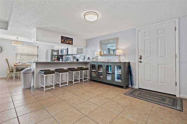 kitchen featuring kitchen peninsula, a textured ceiling, a breakfast bar, and light tile patterned floors