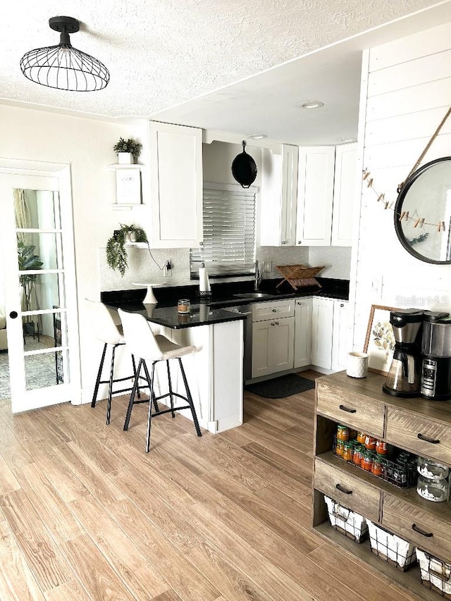 kitchen featuring white cabinets, light hardwood / wood-style flooring, and decorative light fixtures