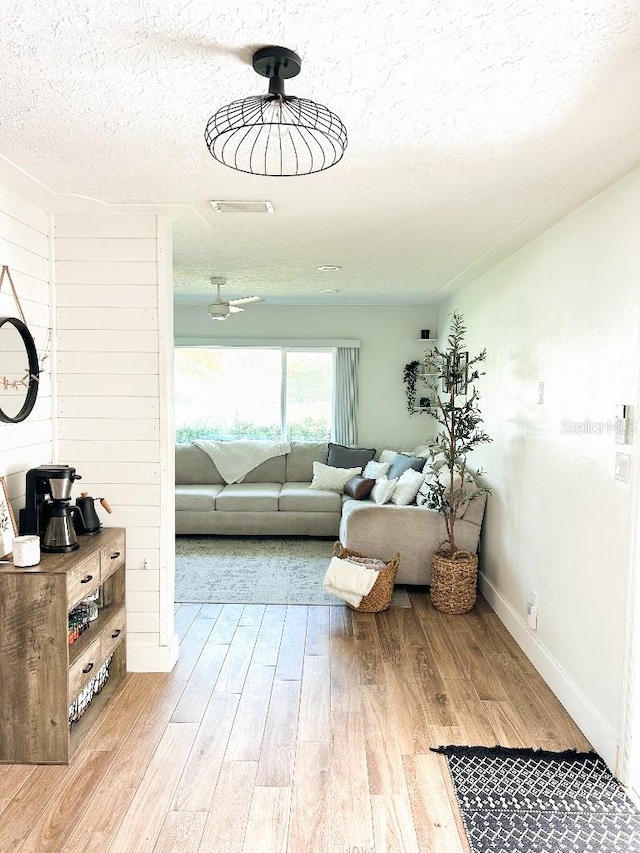 interior space featuring wooden walls, light hardwood / wood-style flooring, and a textured ceiling