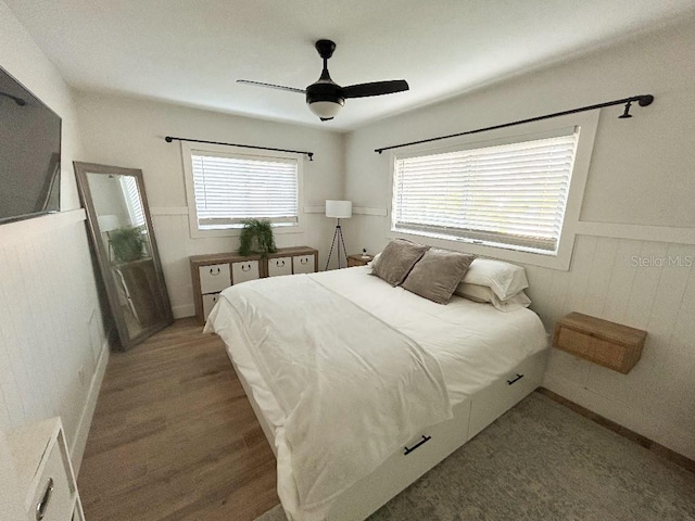 bedroom featuring ceiling fan, multiple windows, and dark hardwood / wood-style floors