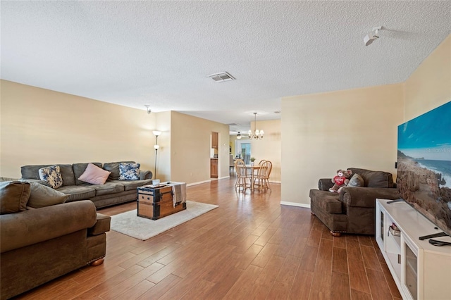 living room with hardwood / wood-style floors, a textured ceiling, and a chandelier