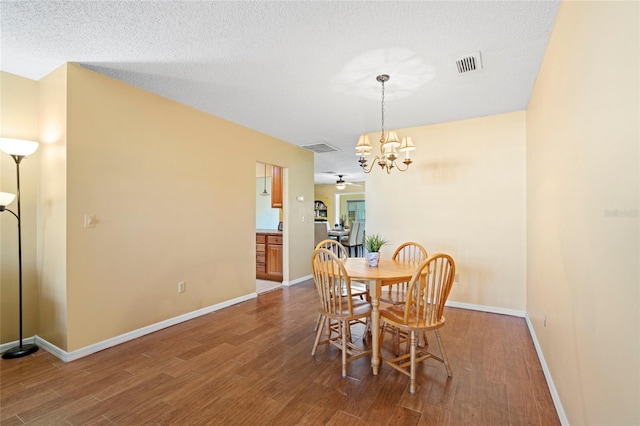 dining space featuring a textured ceiling, hardwood / wood-style floors, and ceiling fan with notable chandelier