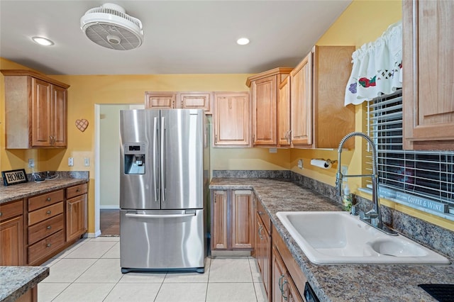 kitchen with dark stone countertops, sink, light tile patterned floors, and stainless steel refrigerator with ice dispenser