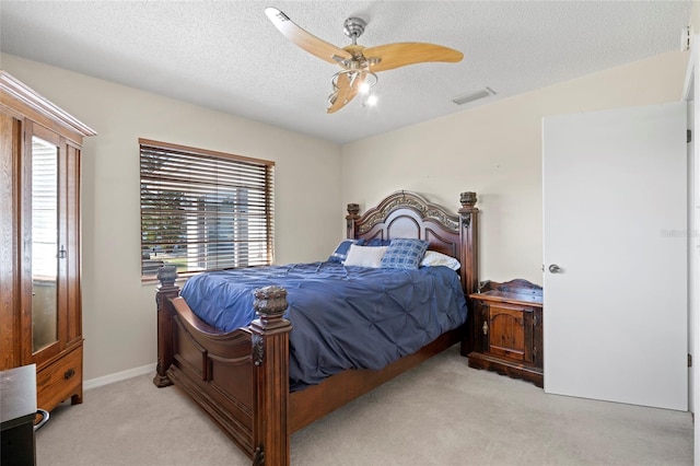 bedroom with a textured ceiling, light colored carpet, and ceiling fan