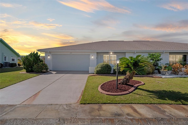 ranch-style house with driveway, a front lawn, an attached garage, and stucco siding