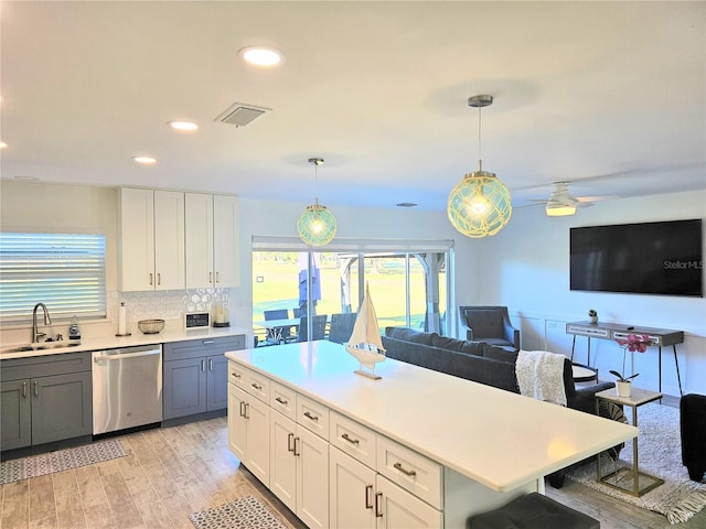 kitchen with visible vents, open floor plan, light countertops, stainless steel dishwasher, and a sink