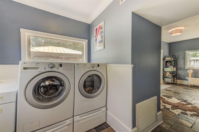 clothes washing area with crown molding, washer and dryer, and plenty of natural light