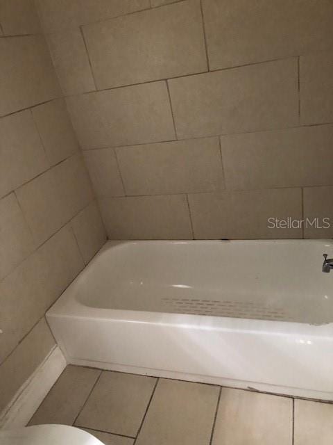 bathroom with a tub, tile patterned flooring, and toilet