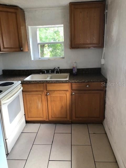 kitchen featuring light tile patterned floors, white electric stove, and sink