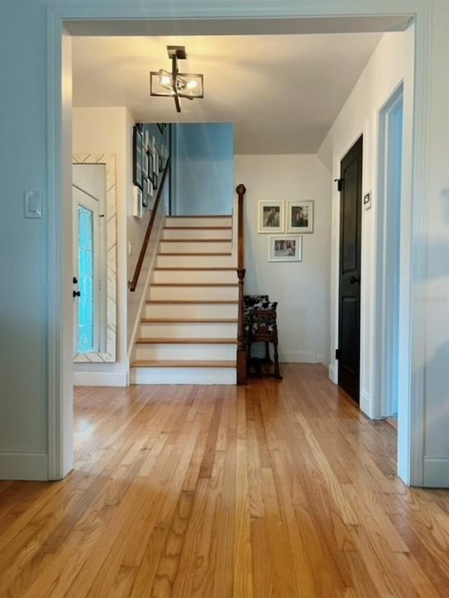 staircase with a notable chandelier and hardwood / wood-style flooring