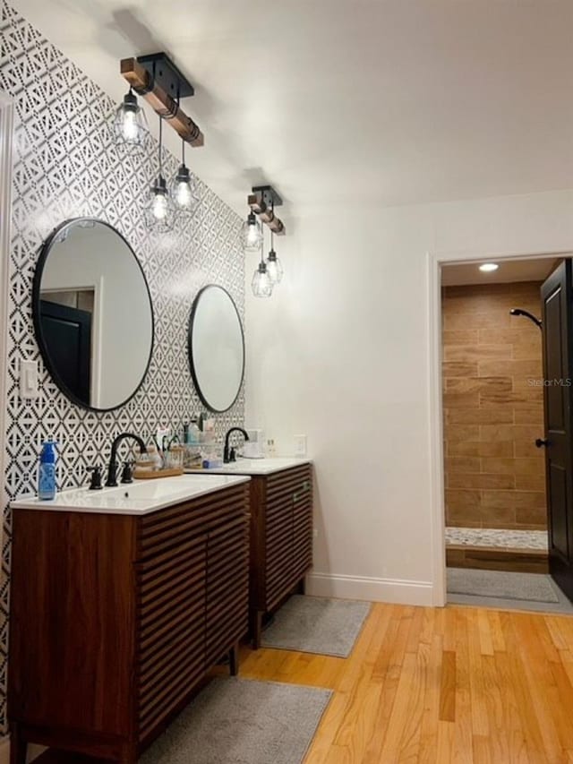 bathroom featuring a tile shower, decorative backsplash, hardwood / wood-style floors, and vanity