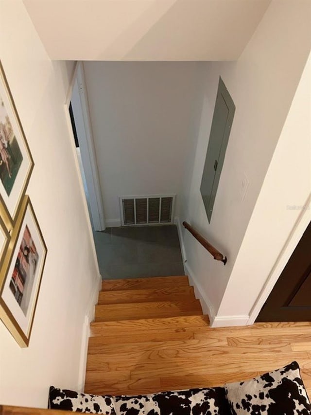 stairway featuring hardwood / wood-style floors and electric panel