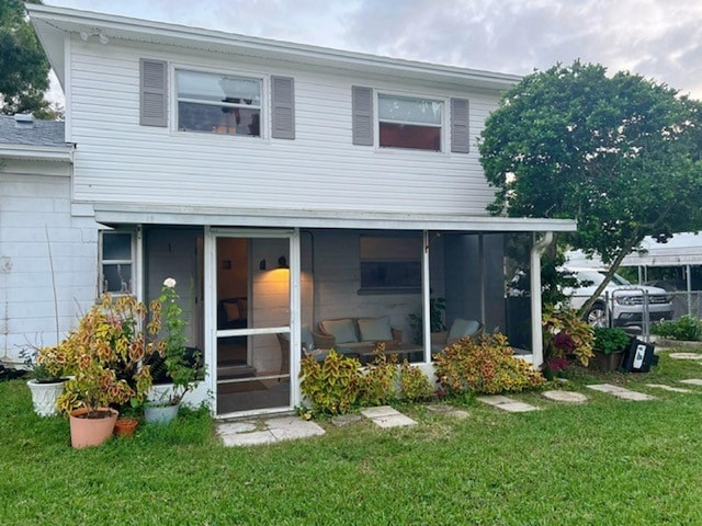 view of front of house with a sunroom and a front lawn