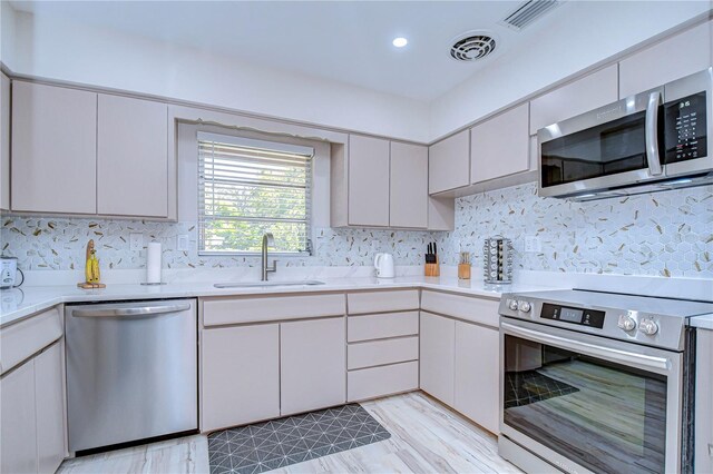 1802 E Hamilton Ave, Tampa, FL 33610 - kitchen with appliances with stainless steel finishes, decorative backsplash, and light wood-style floors