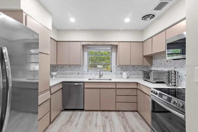 1802 E Hamilton Ave, Tampa, FL 33610 - kitchen with appliances with stainless steel finishes, light countertops, backsplash, and light wood-style floors