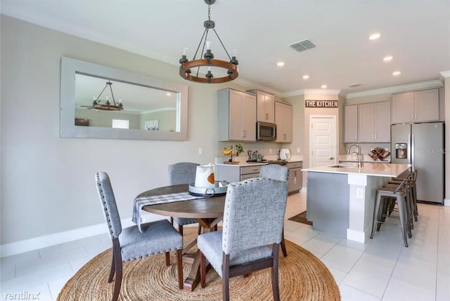 dining room with a chandelier, sink, light tile patterned floors, and ornamental molding