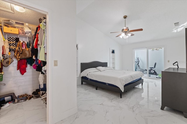 bedroom featuring lofted ceiling, a walk in closet, ceiling fan, a textured ceiling, and a closet