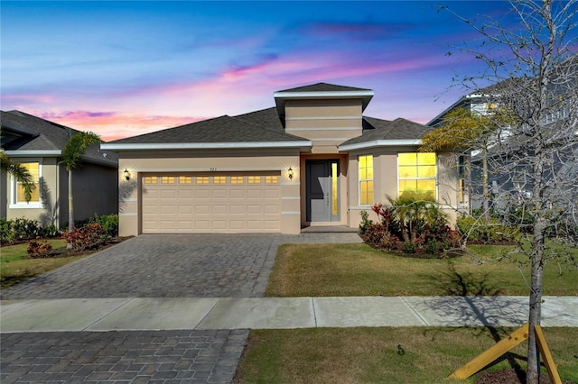 prairie-style house featuring a garage and a yard