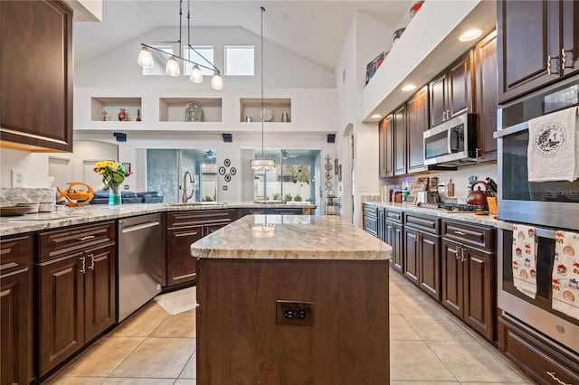 kitchen with high vaulted ceiling, stainless steel appliances, sink, dark brown cabinetry, and a center island