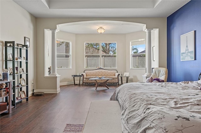 bedroom featuring dark hardwood / wood-style floors, a textured ceiling, and ornate columns